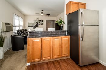 A kitchen with a black fridge and wooden cabinets.at Garwood Gardens Apartments, Garwood